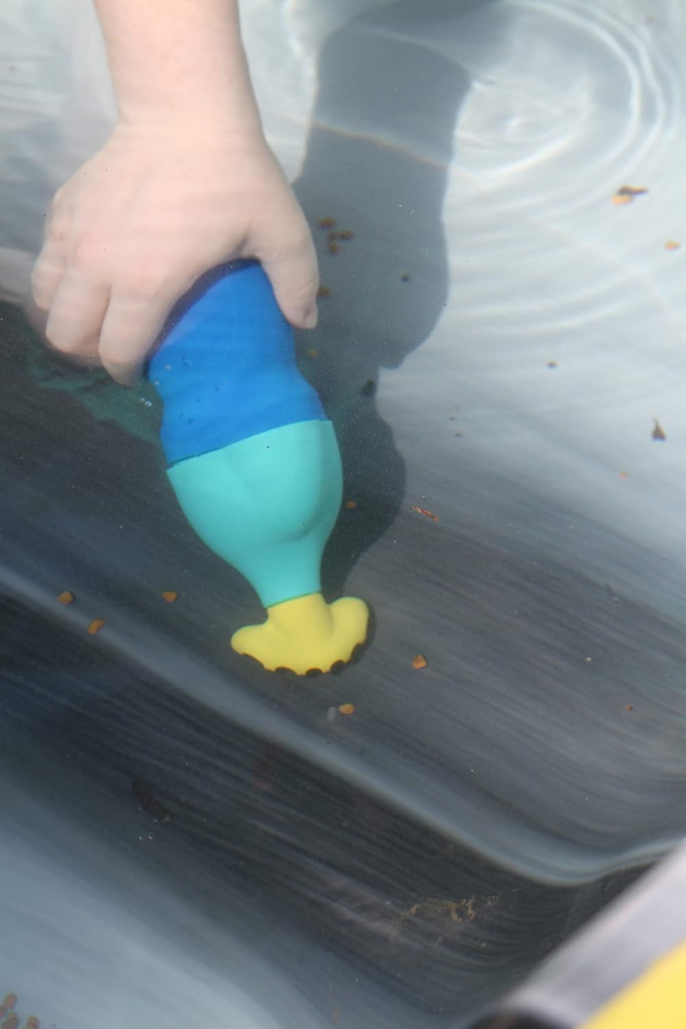 A hand holds the Pool Goods Water Tech Grit-Gitter Spa Vacuum Cleaner (60A0102) underwater, with small brown particles floating nearby.