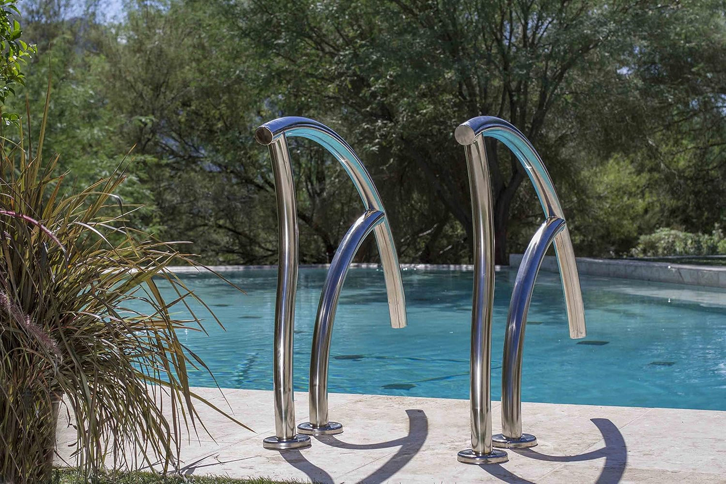 The SR Smith Designer Figure 4 Grab Rail Pair in durable 304 stainless steel is installed by the pool, surrounded by lush greenery.