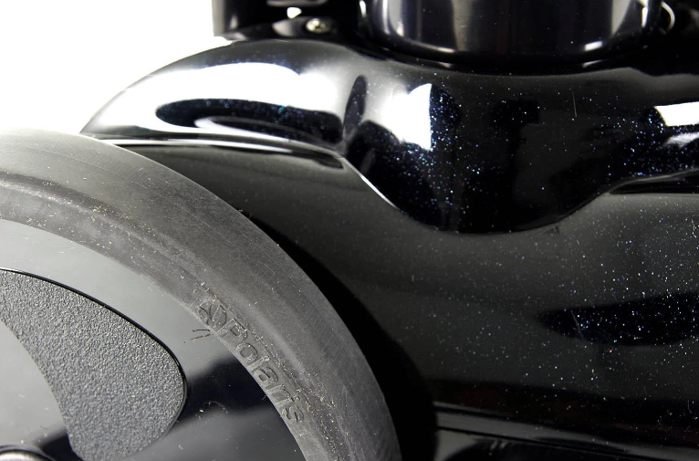 Close-up of a black, glossy wheel from the Polaris Vac-Sweep 280, Black Max, Pressure Side Pool Cleaner (F5B), highlighting its sleek design with curved surfaces and reflective highlights. Ideal for maintaining in-ground pools.