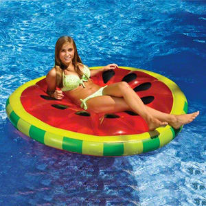 A person in a green swimsuit is lounging on the Swimline Watermelon Slice Island Pool Float (model 90544) in a swimming pool.
