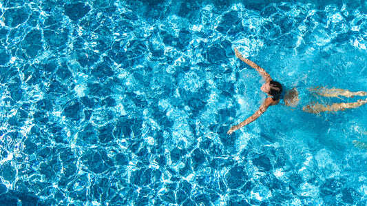 A clean pool with a woman swimming in it. The pool has been sanitized with pool shock.