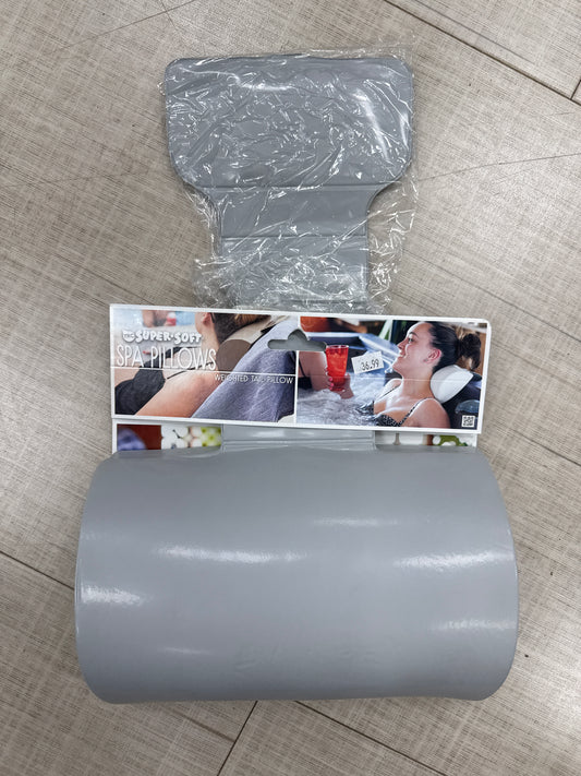 The Weighted Tail Spa Pillow by Pool Goods is displayed in gray on a tile floor, with packaging that shows people using the pillow and a label that reads "Super Soft Spa Pillows.